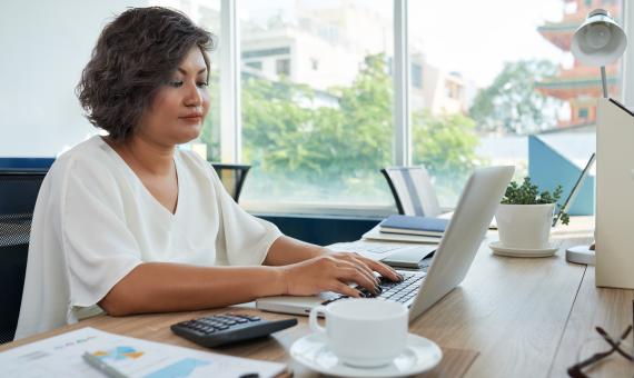 woman-with-short-wavy-hair-sitting-desk-office-working-laptop